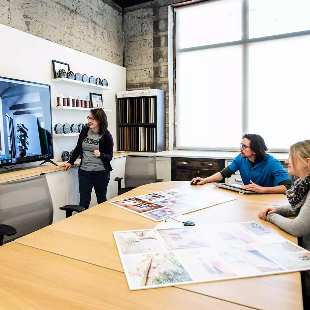 Team of architects and designers at conference room table reviewing design on TV screen