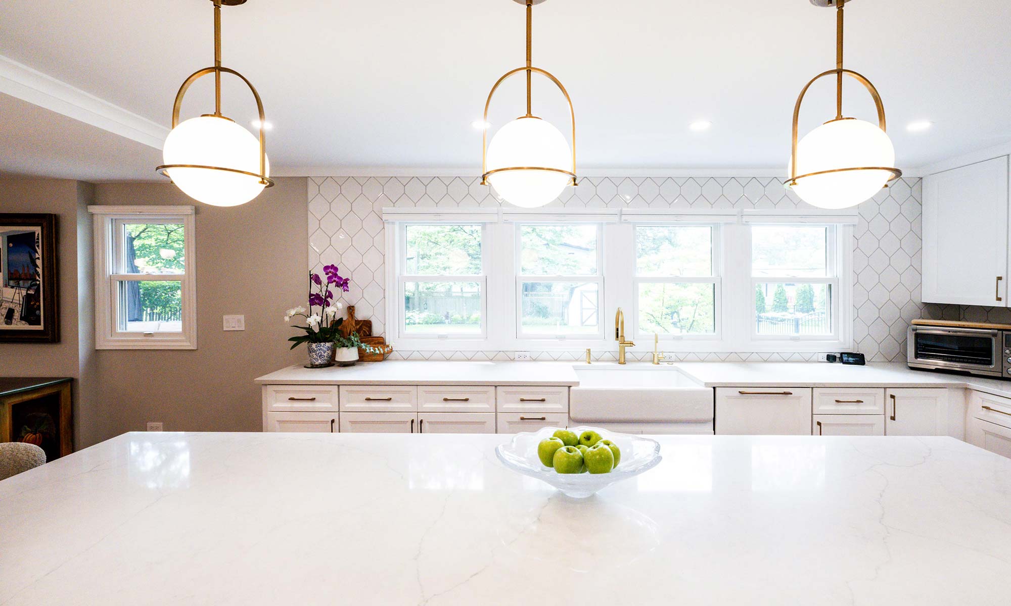 A kitchen with white cabinets and pendant lights