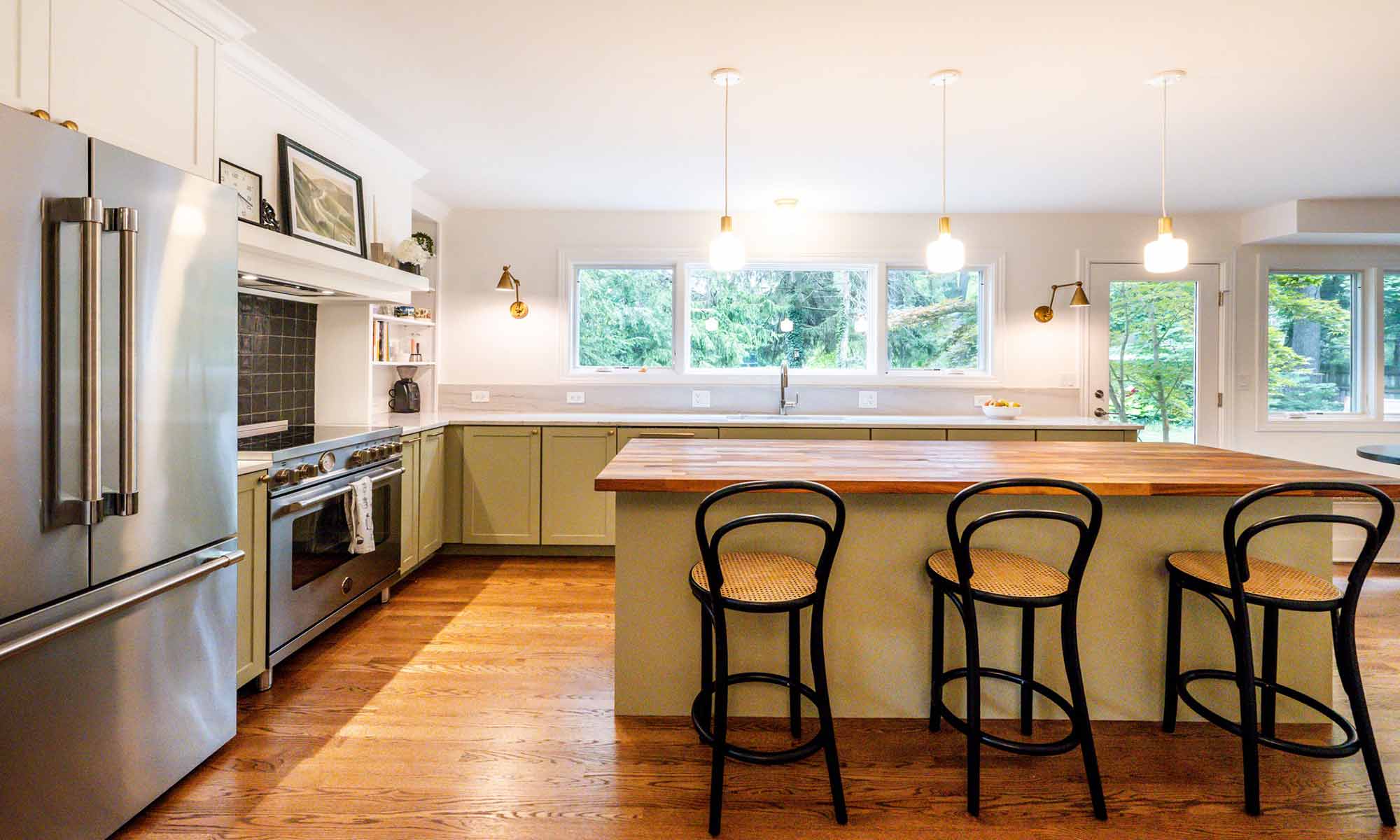 luxury kitchen remodel with green cabinets and butcherblock island and three stools