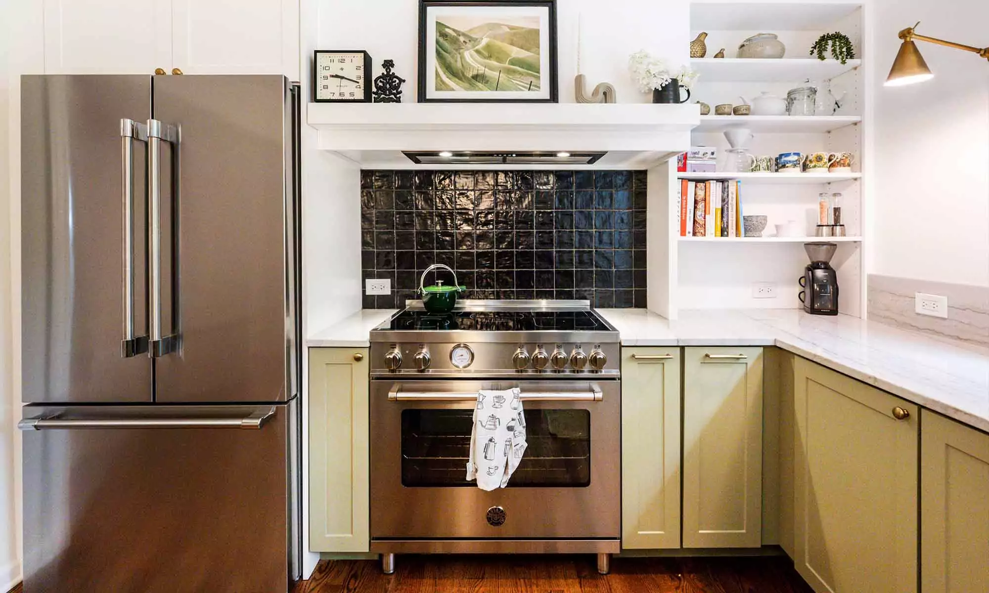 closeup view of stainless steel range and black backsplash tile in luxury kitchen remodel with green cabinets