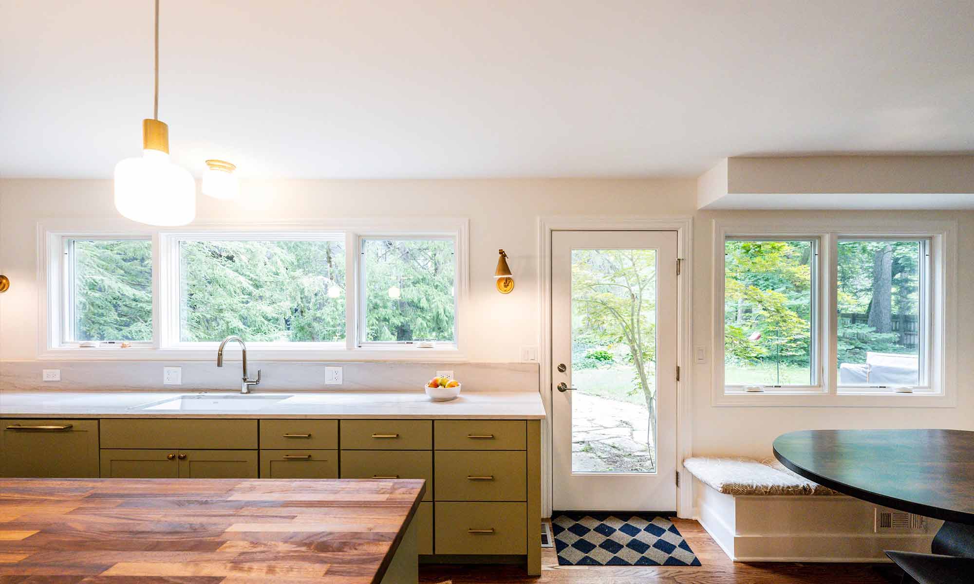 looking towards backyard through windows and door in luxury kitchen remodel with green cabinets