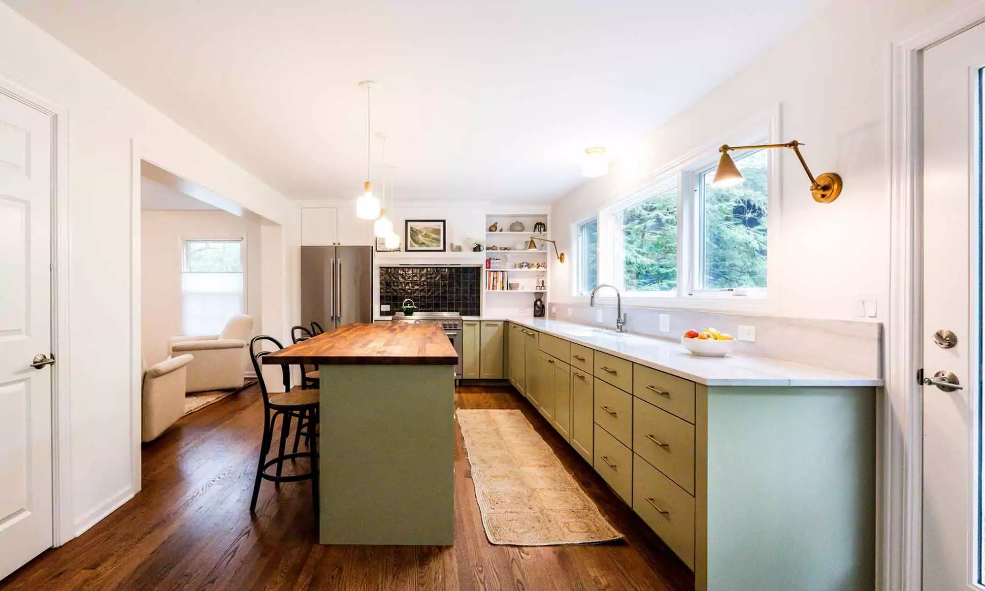 luxury kitchen remodel with green cabinets and butcherblock island and three stools