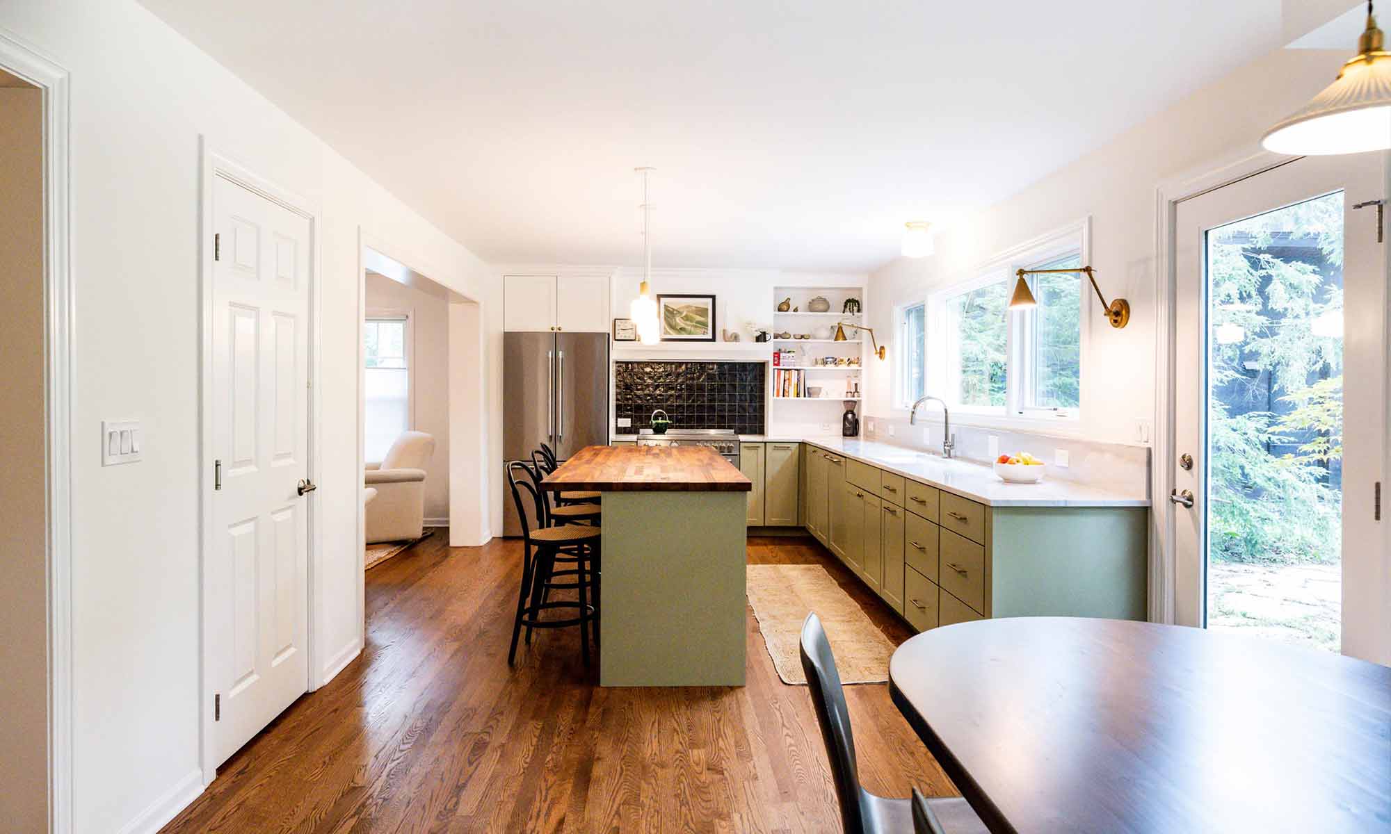 luxury kitchen remodel with green cabinets and butcherblock island and three stools