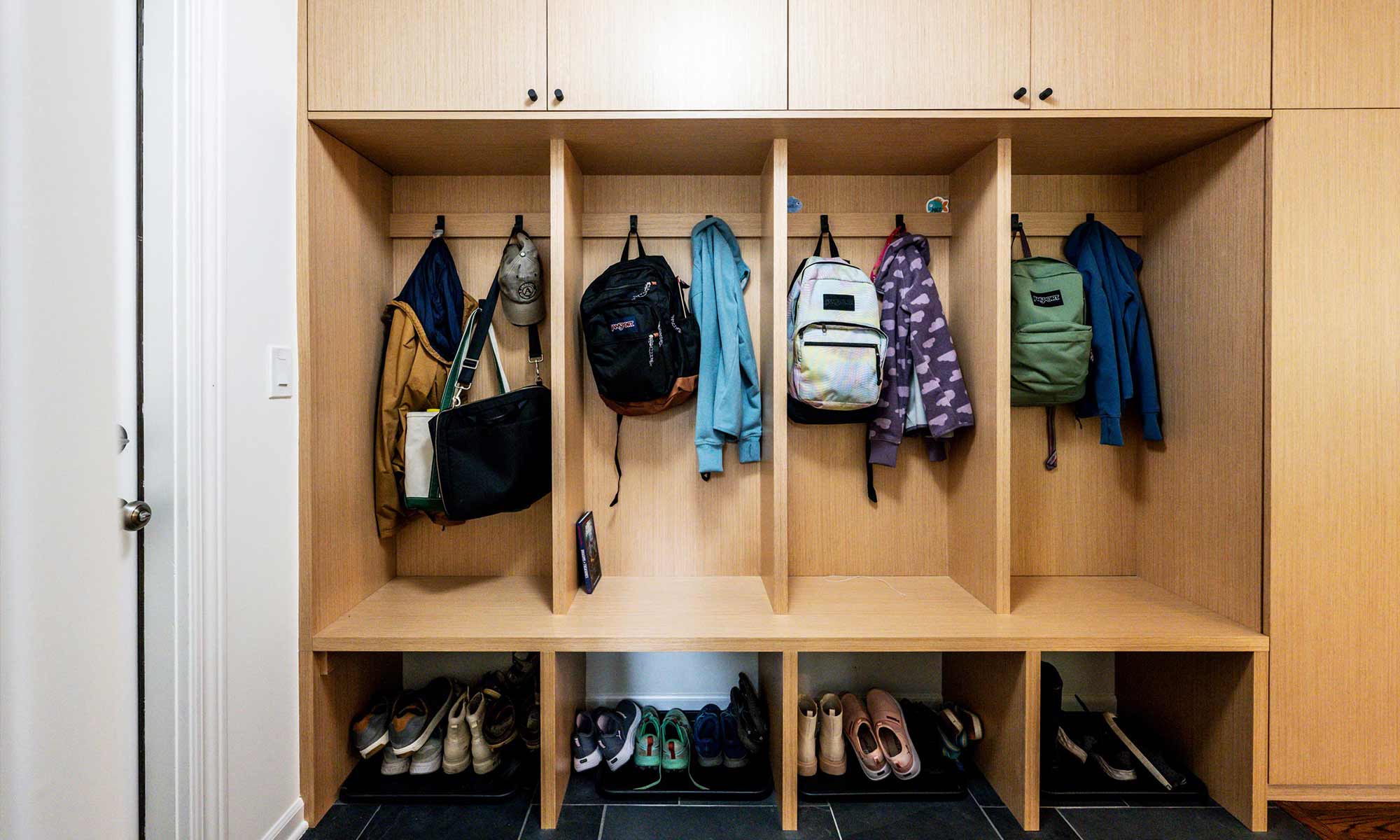 white oak mudroom built-ins in luxury home remodel with hanging backpacks