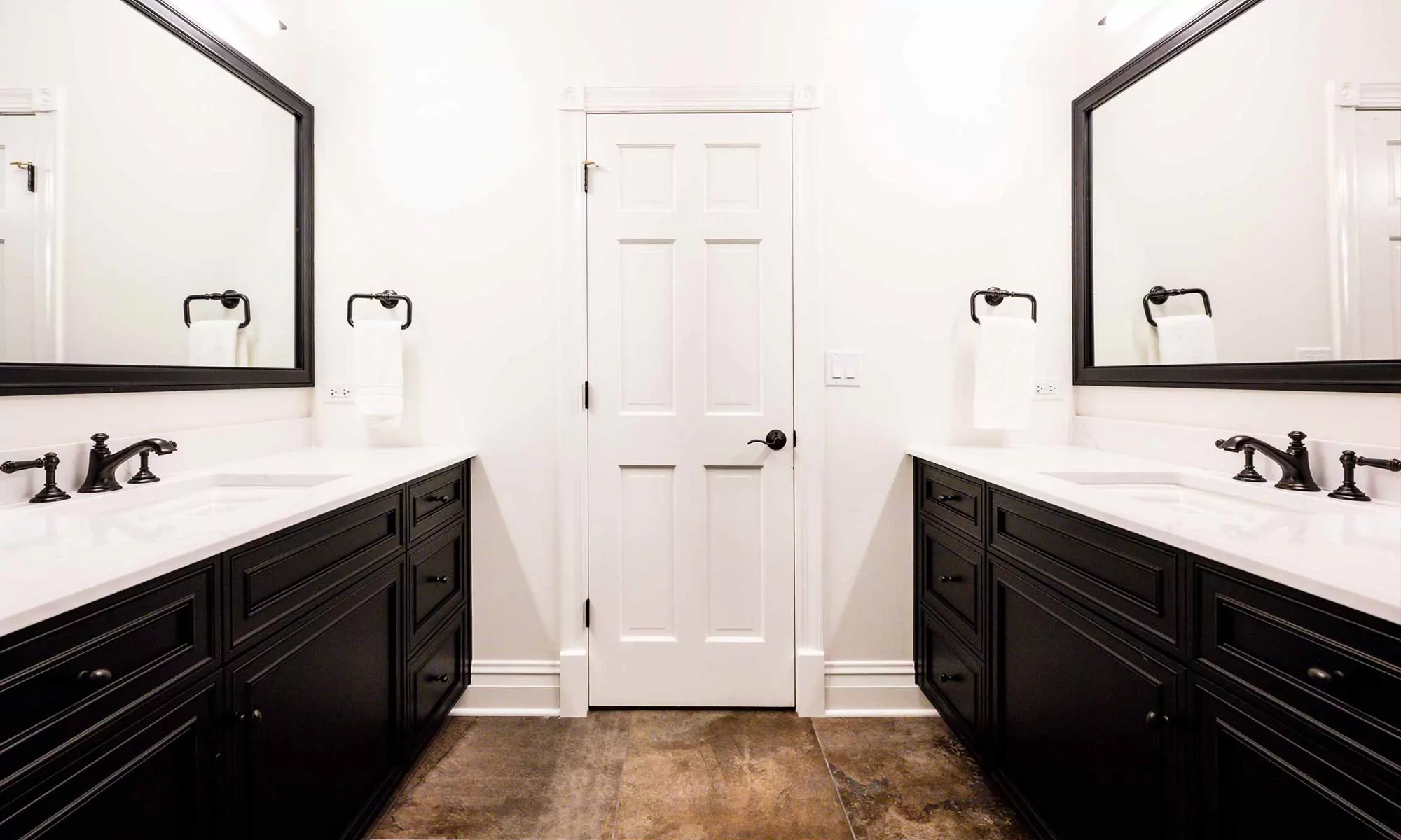 bathroom door flanked by vanities on both sides