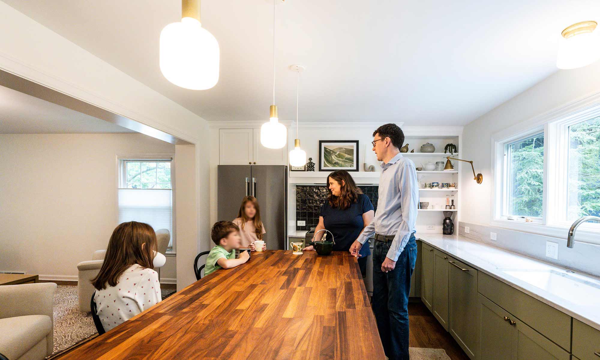 Family of five gathered around butcher block kitchen island in luxury kitchen remodel