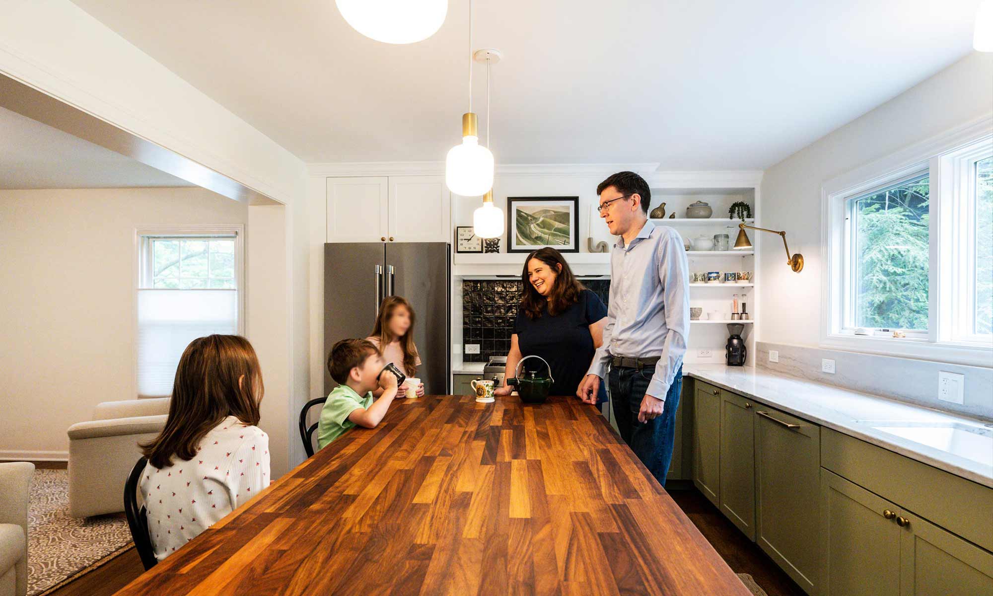 Family of five gathered around butcher block kitchen island in luxury kitchen remodel