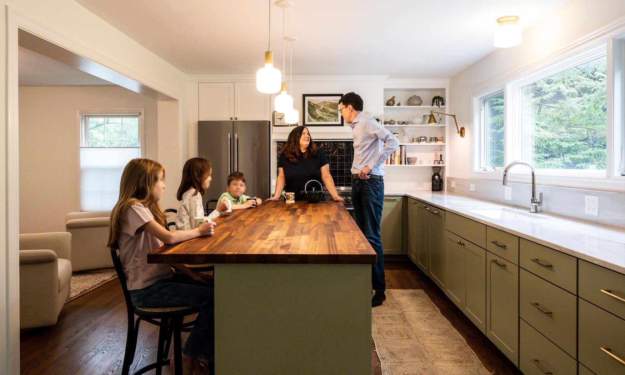 Family of five gathered around butcher block kitchen island in luxury kitchen remodel