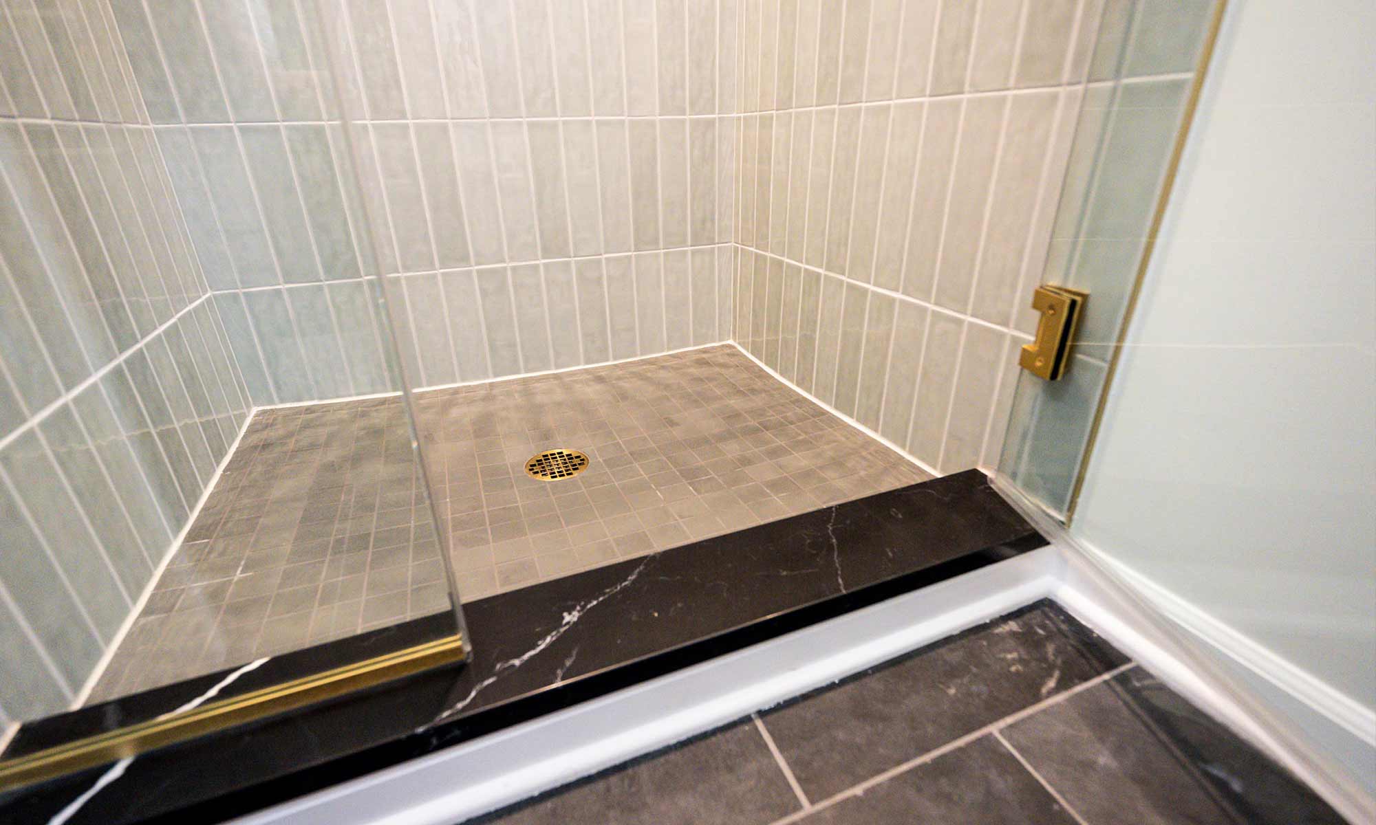 closeup view of black stone shower curb in luxury bathroom remodel