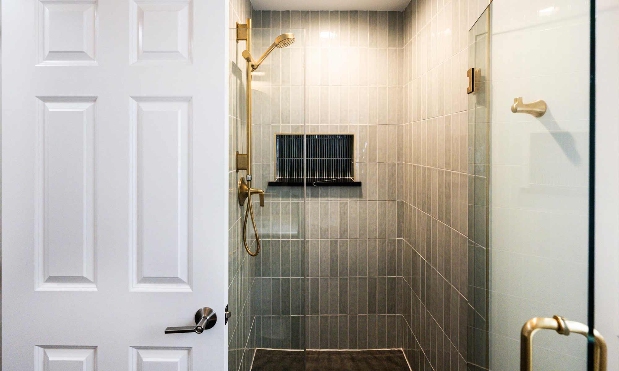 Luxury shower remodel with green tile and onyx black recessed shelf