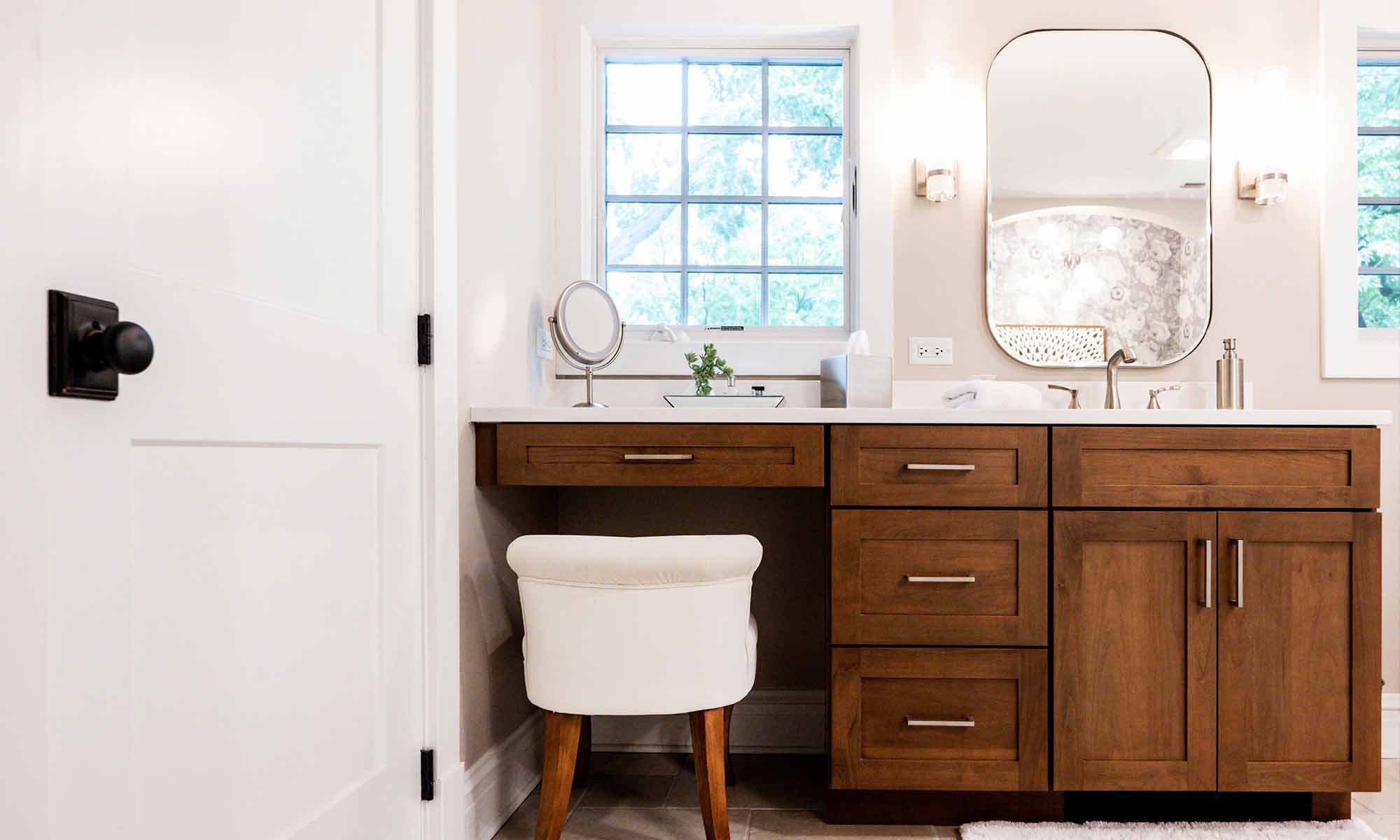 primary bathroom with wood cabinets, windows and makeup station