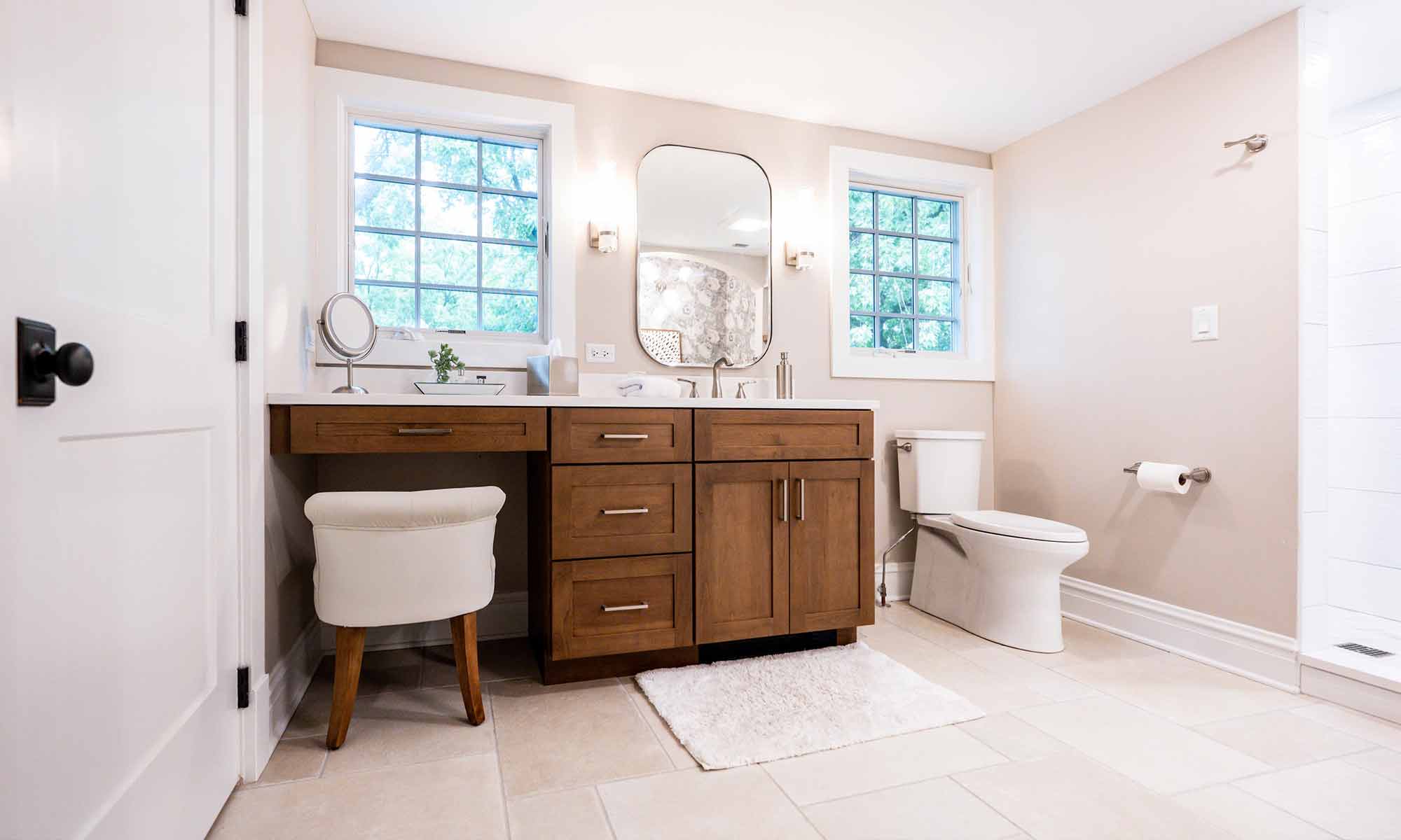 primary bathroom with wood cabinets, windows and makeup station