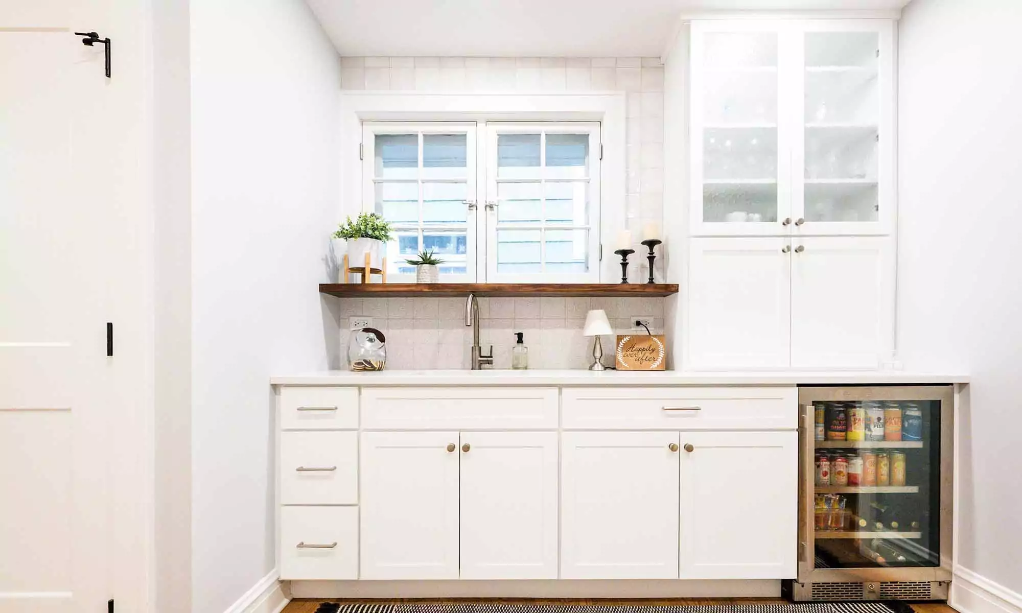 white cabinets at breakfast bar with open wood shelf and window over the sink
