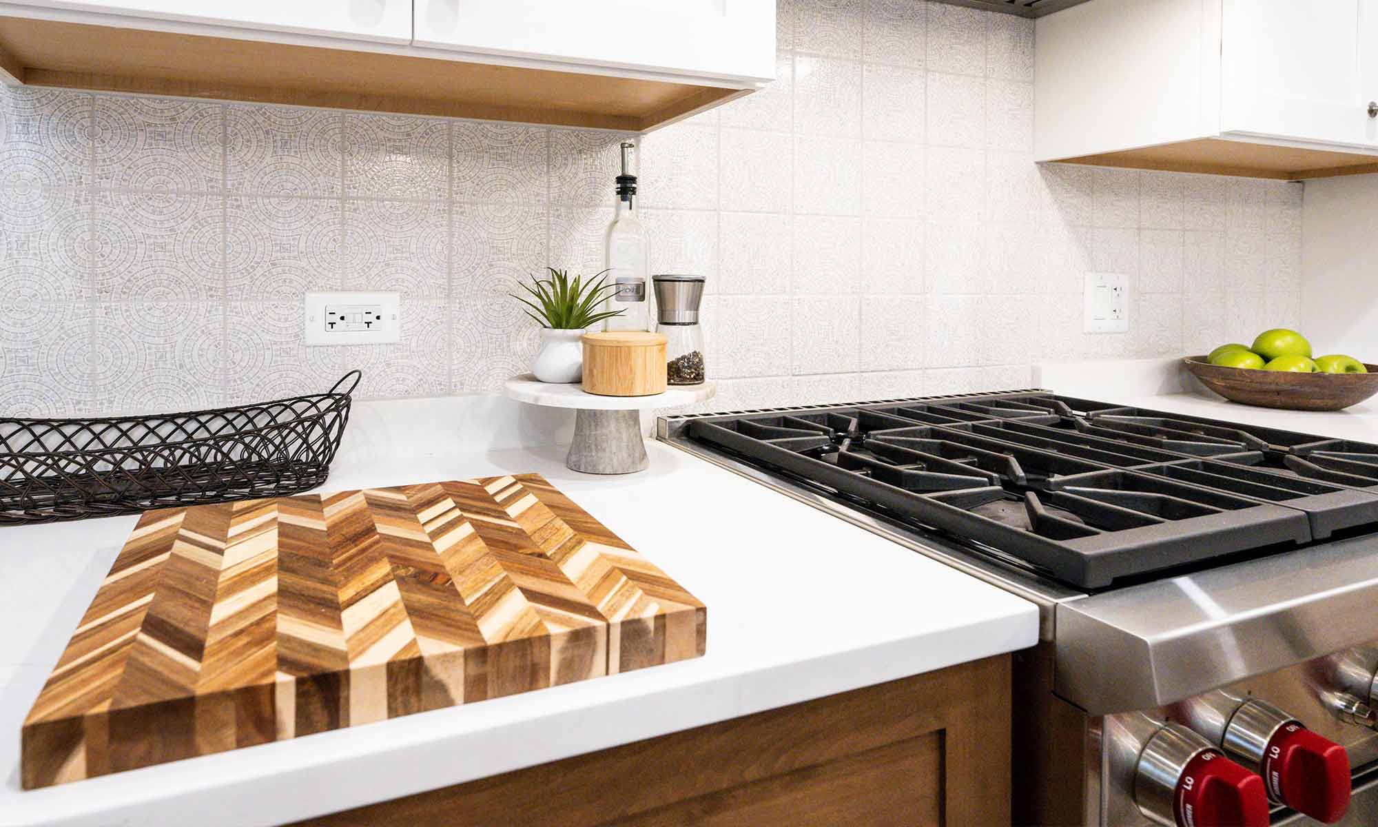 closeup of kitchen range and cutting board on white quartz countertops