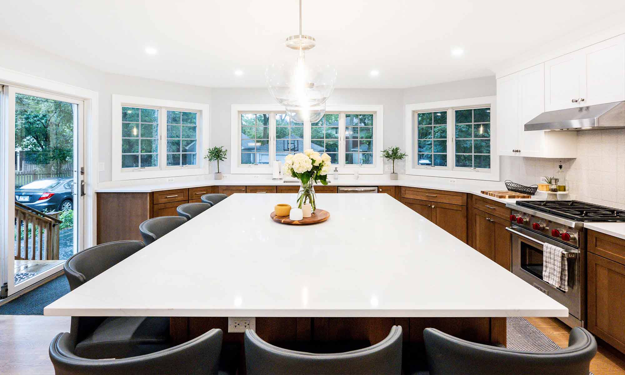 large kitchen island in luxury remodel with eight windows and white quartz countertops