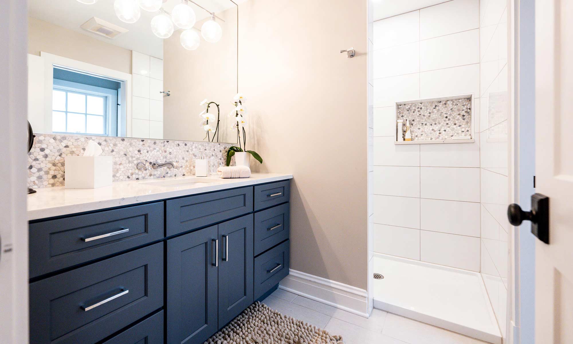 hall bath remodel with blue vanity cabinets and walk-in shower