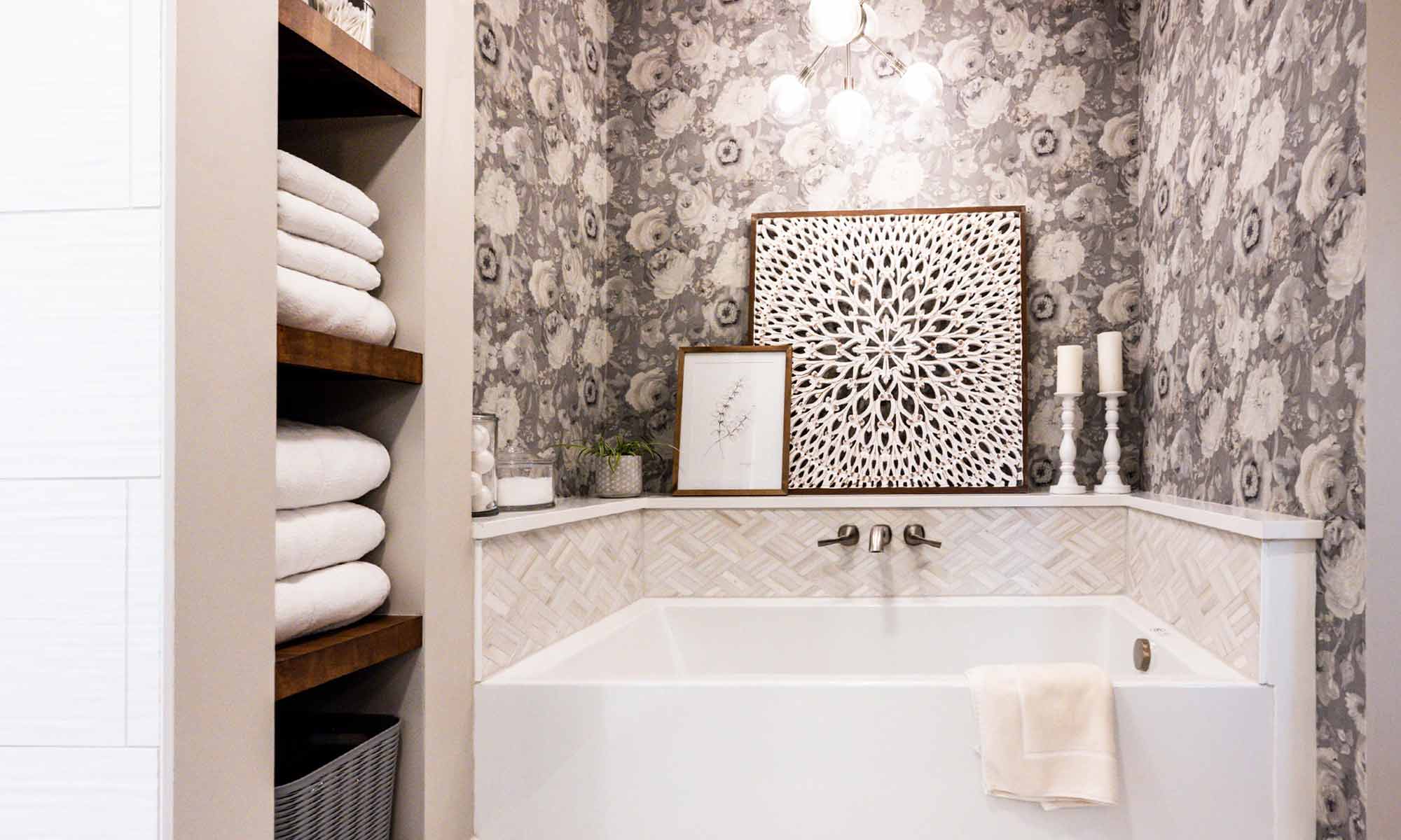 soaking tub with tile and quartz surround and open wood linen shelves