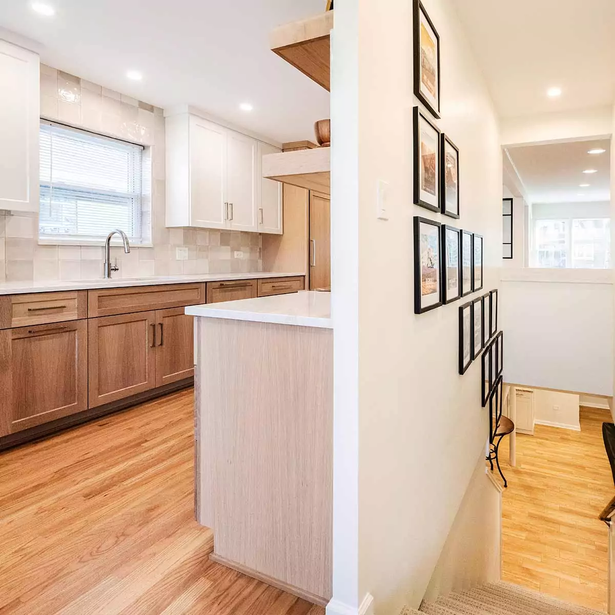 luxury interior remodel view through basement stairs showing open entry and white oak kitchen cabinetry