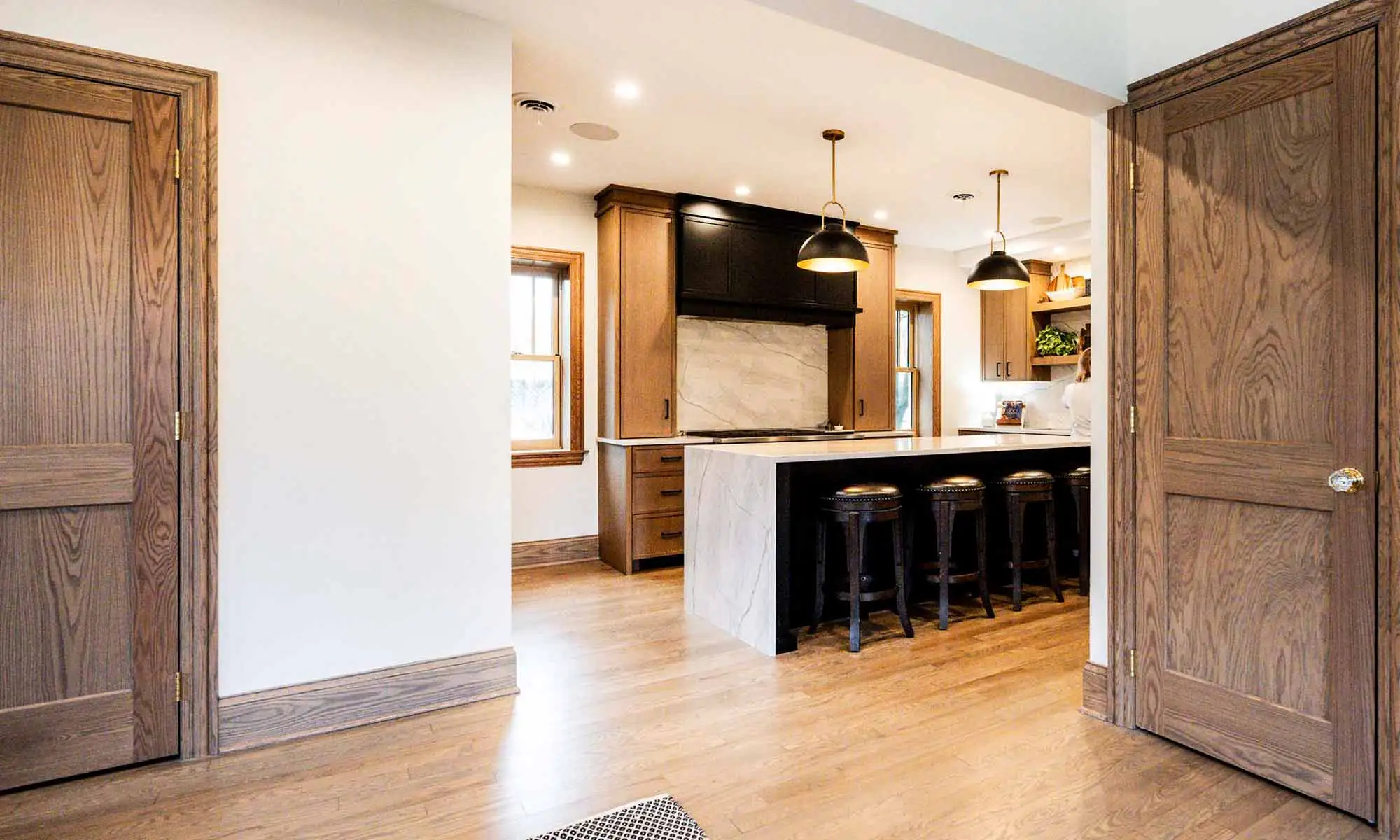 view of luxury kitchen remodel with windows flanking large range wall and white oak cabinetry