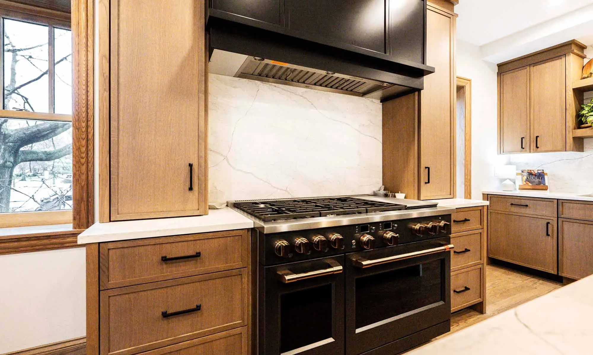 view of luxury kitchen remodel with windows flanking large range wall and white oak cabinetry