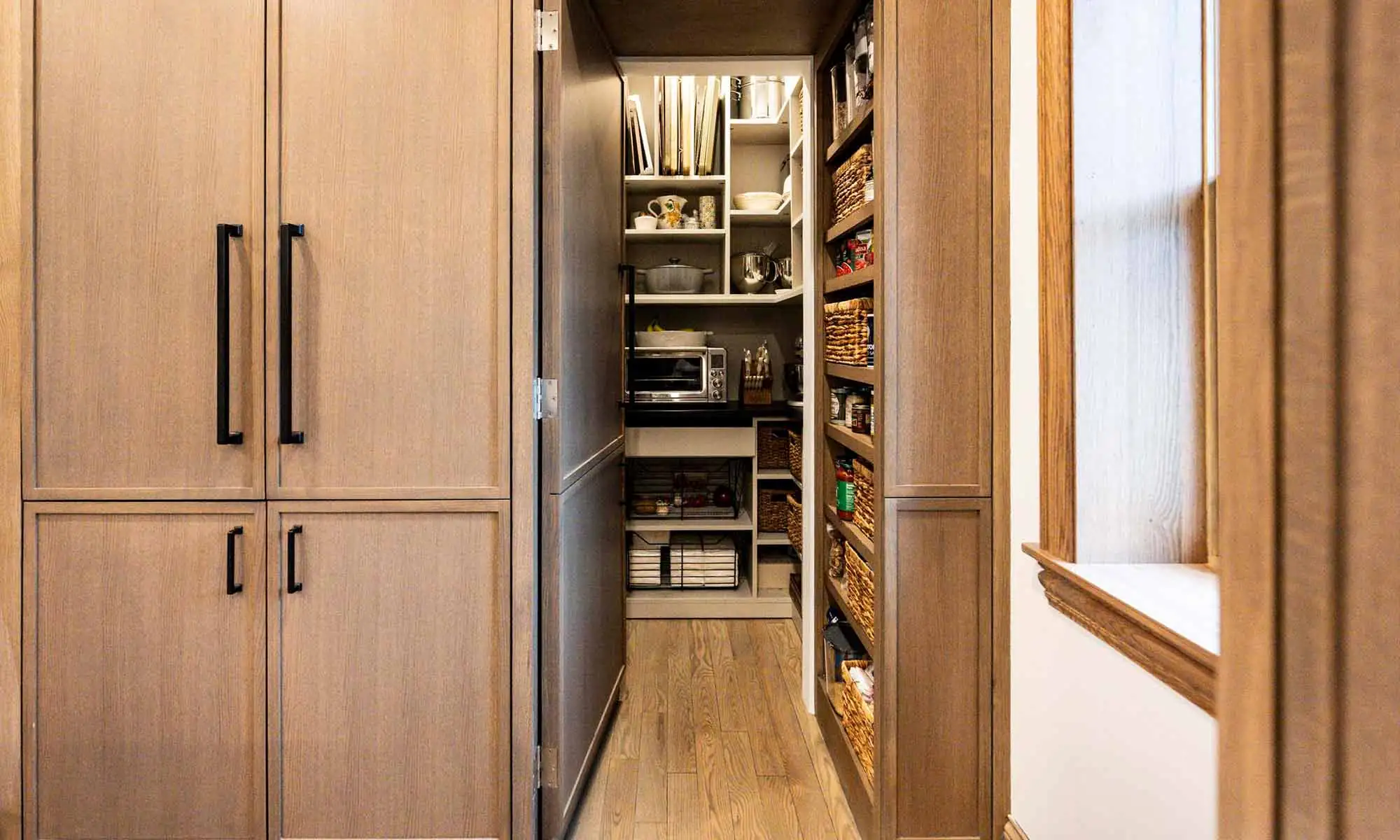 hidden pantry through white oak cabinet doors