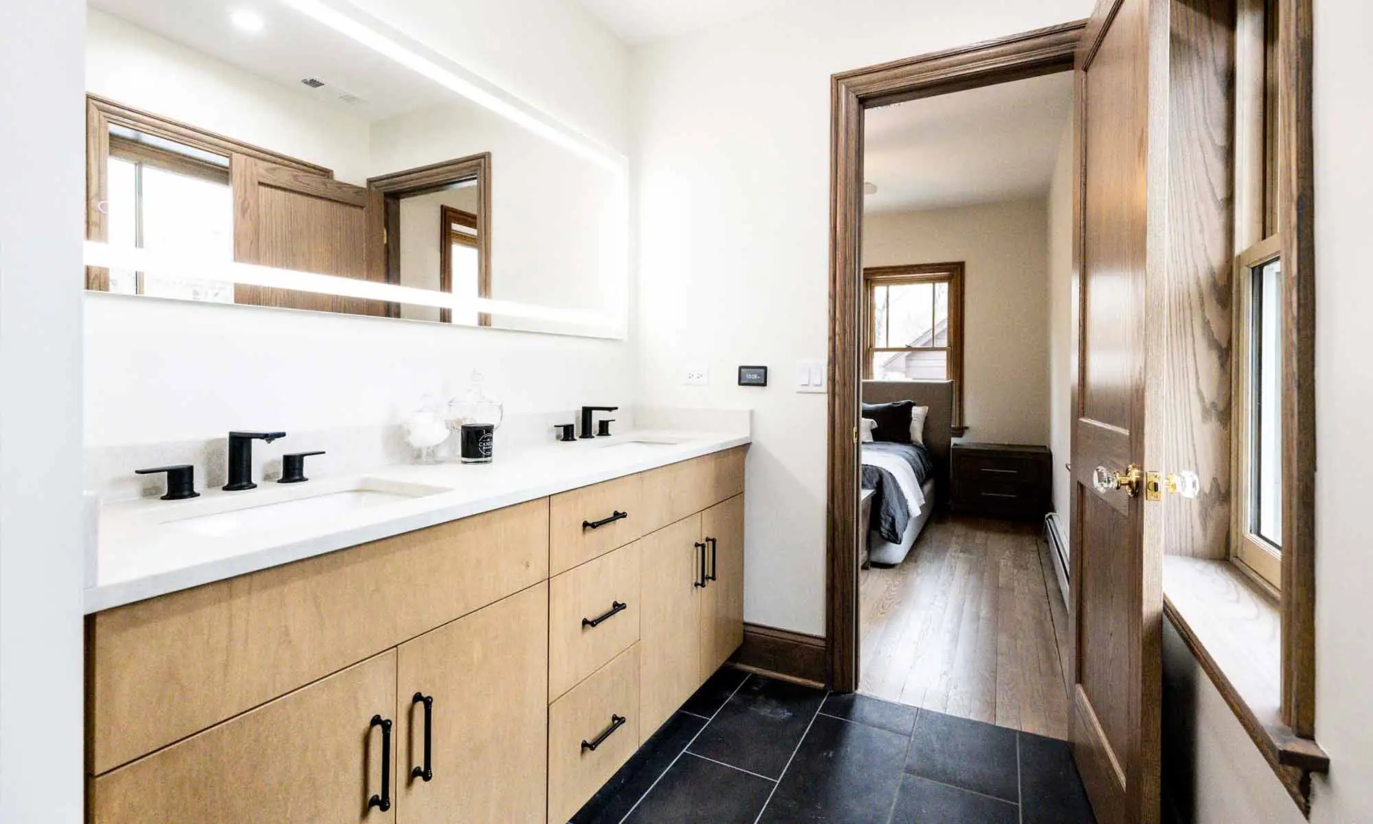 luxury bathroom remodel with light wood cabinets and black plumbing fixtures and lighted mirror