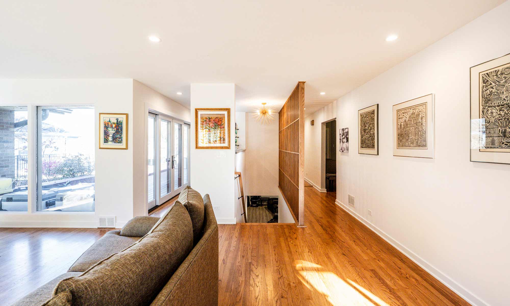 A modern living room with a plush couch and a wall of windows, creating a warm and inviting environment filled with light and a wood feature wall