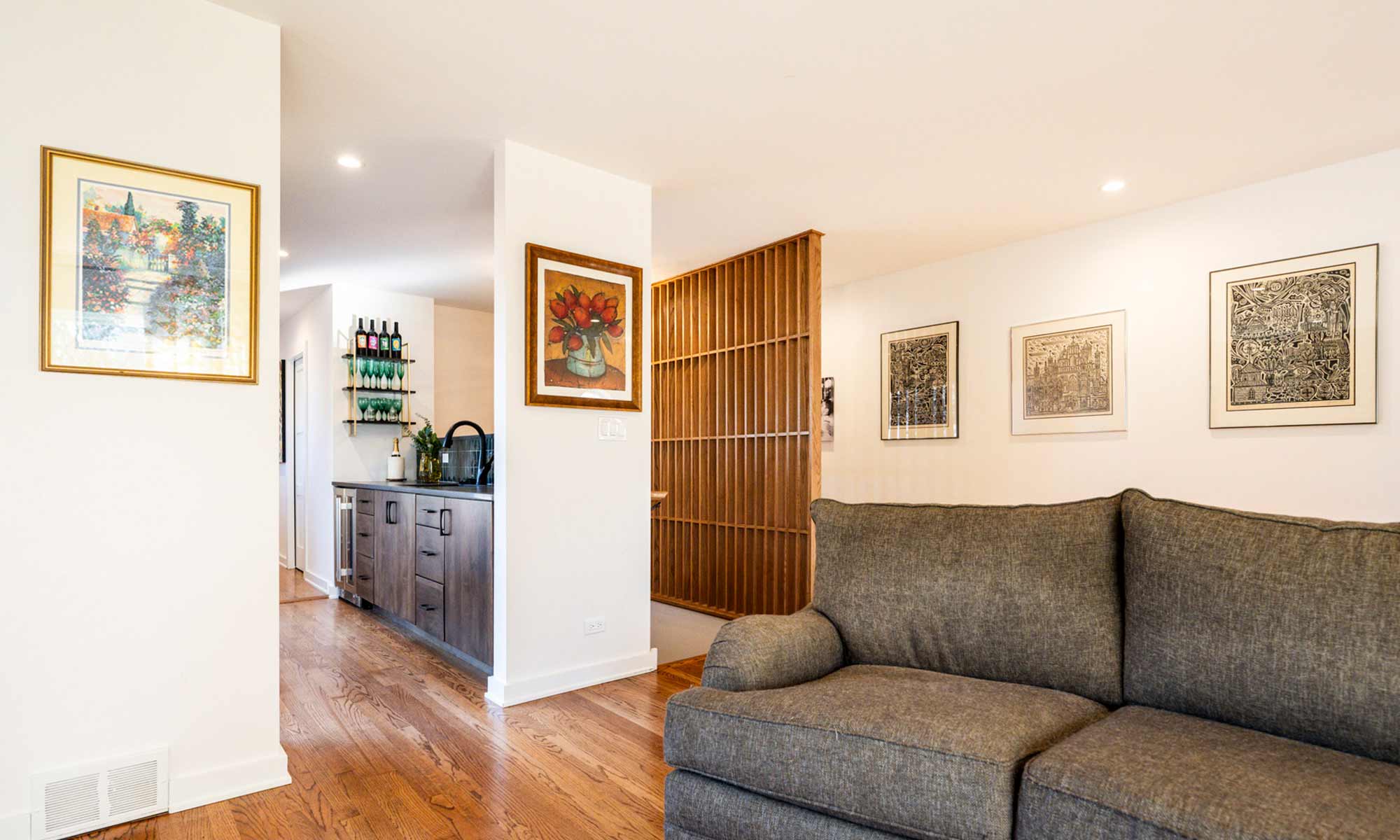 A modern living room with a plush couch and a wall of windows, creating a warm and inviting environment filled with light and a wood feature wall
