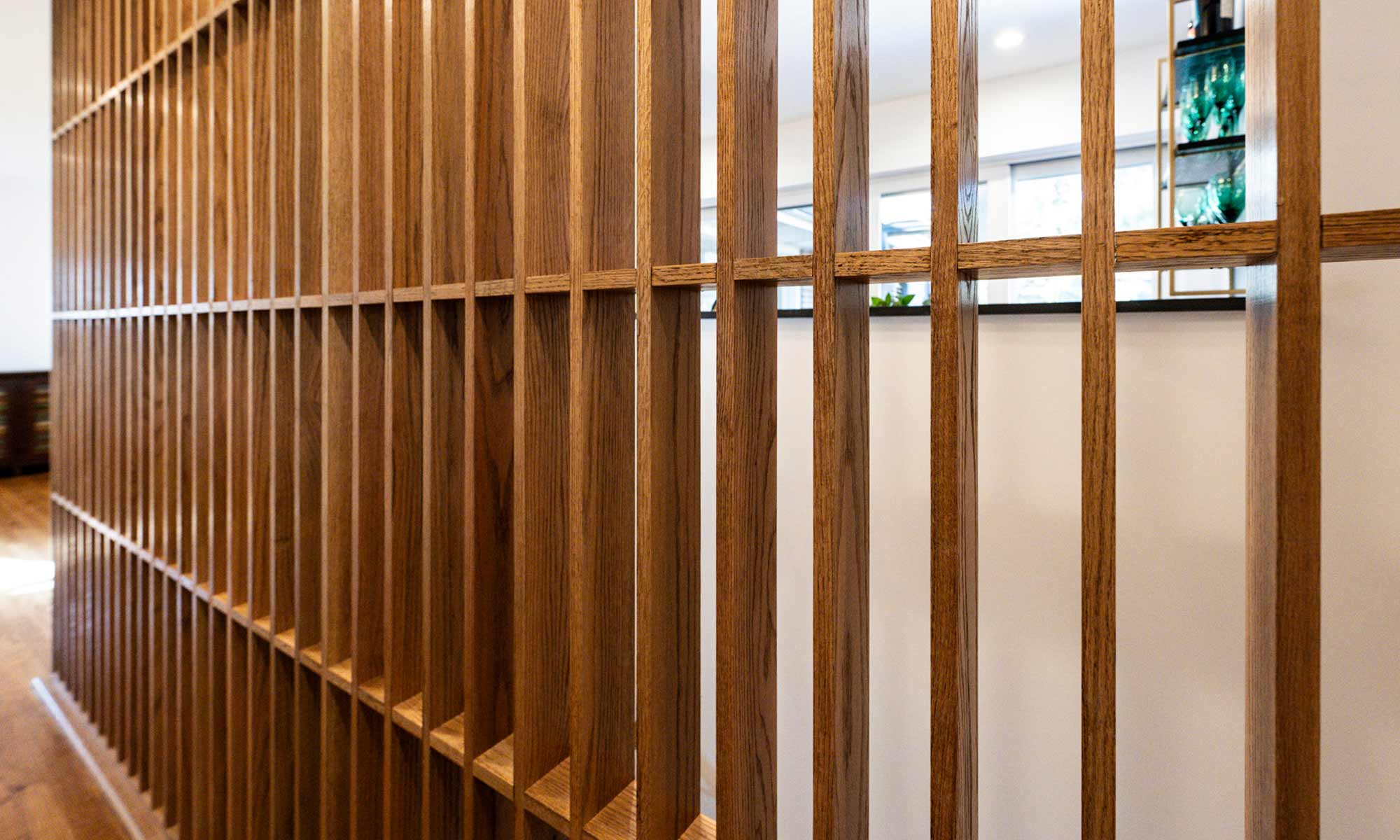 closeup image of open wood slatted feature wall in oak along a basement stair